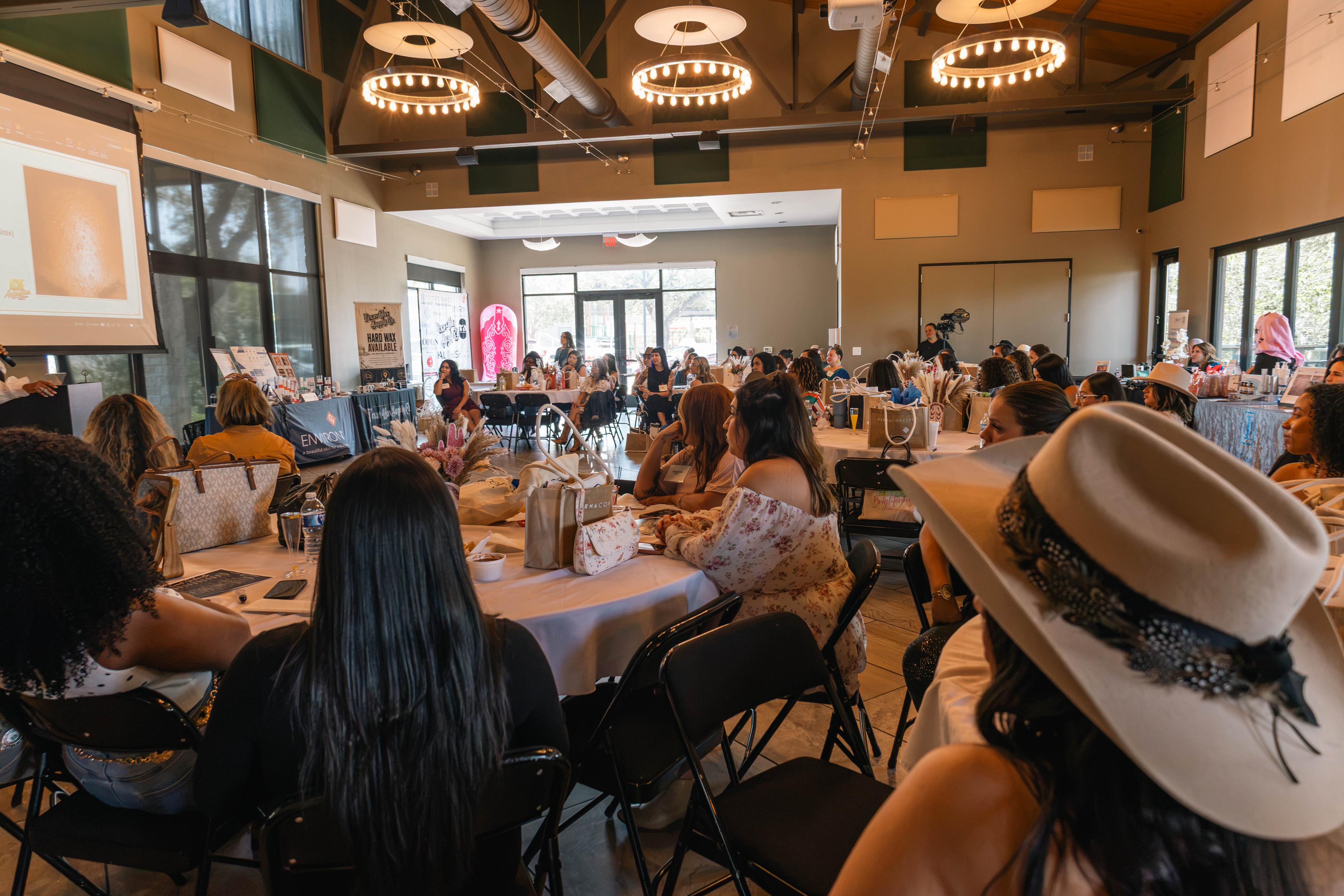 Estheticians gathered around tables during a Glow & Gather Vol. 3 presentation at the Voigt Center
