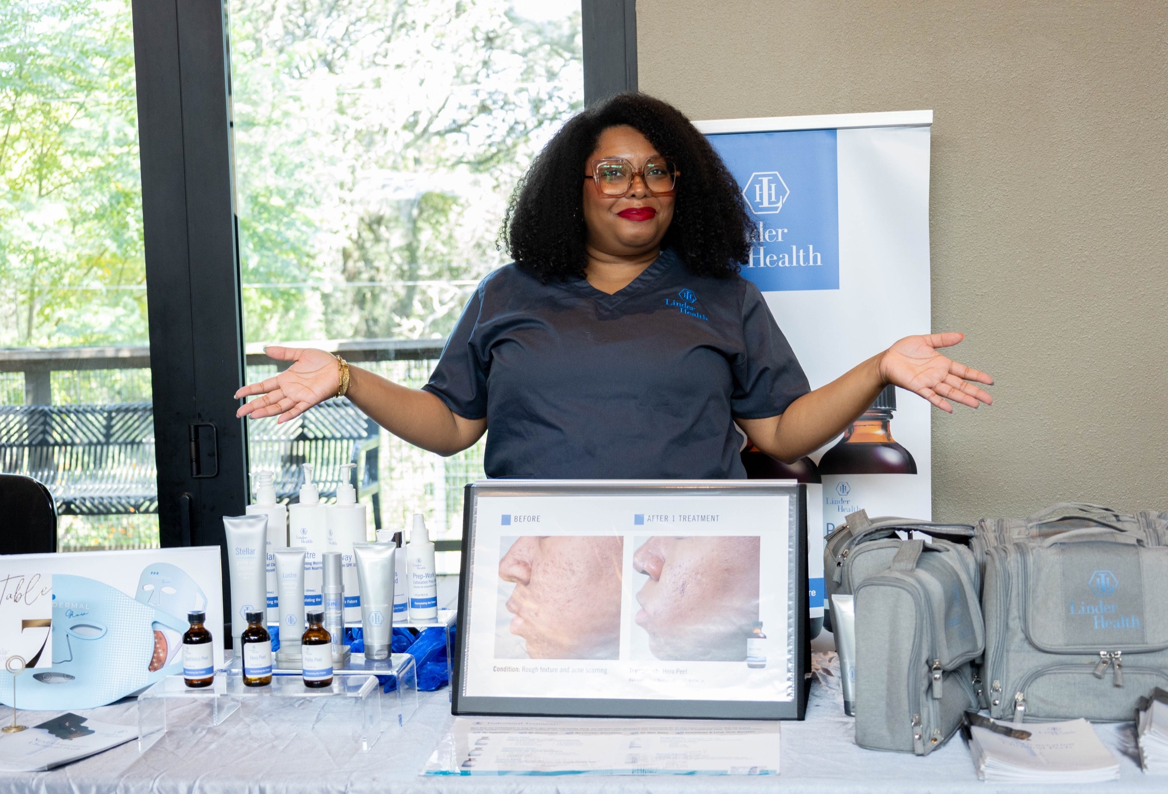 A skincare vendor welcomes attendees from behind a table of blue-and-white products