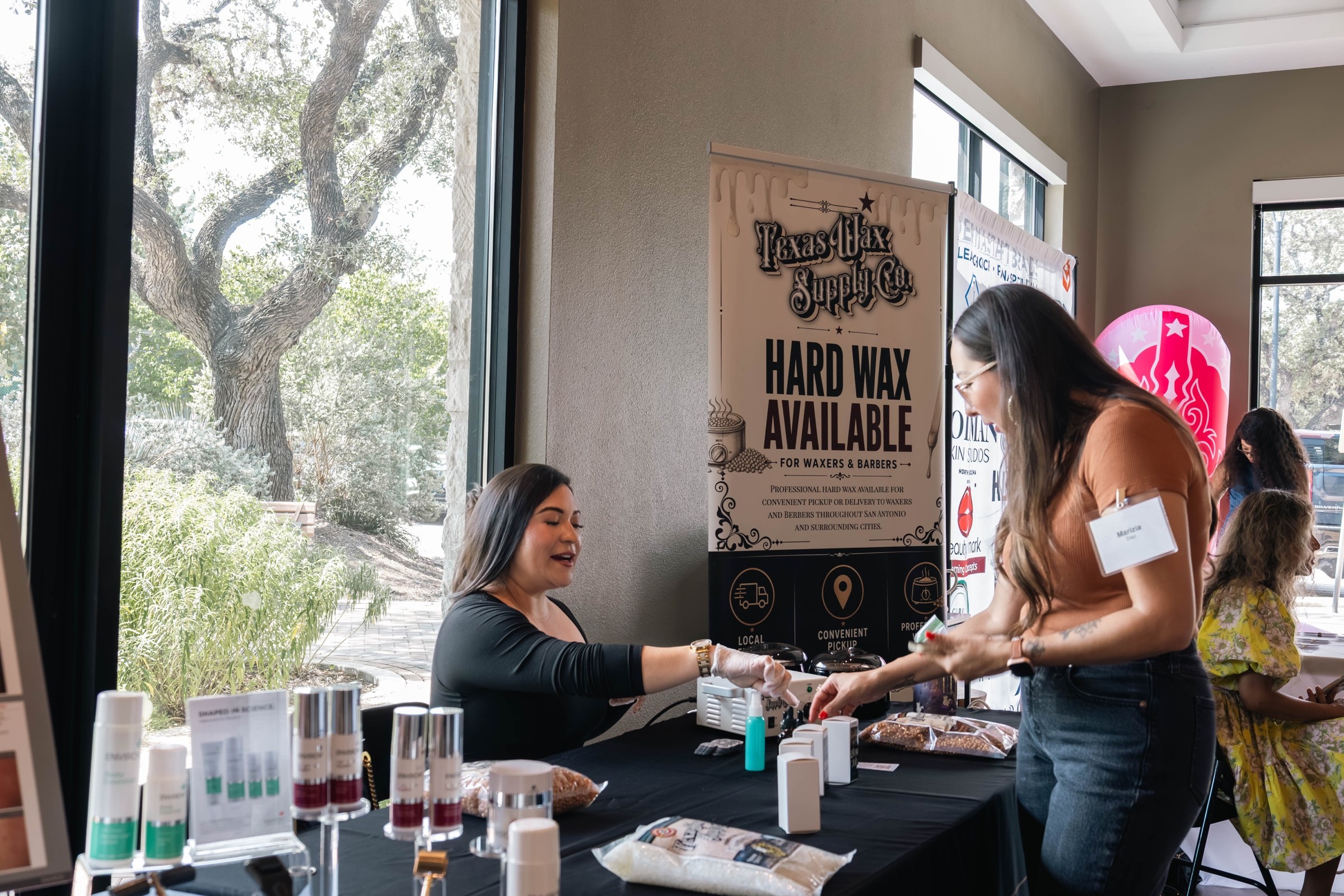 A vendor shares a product with an attendee across a display table