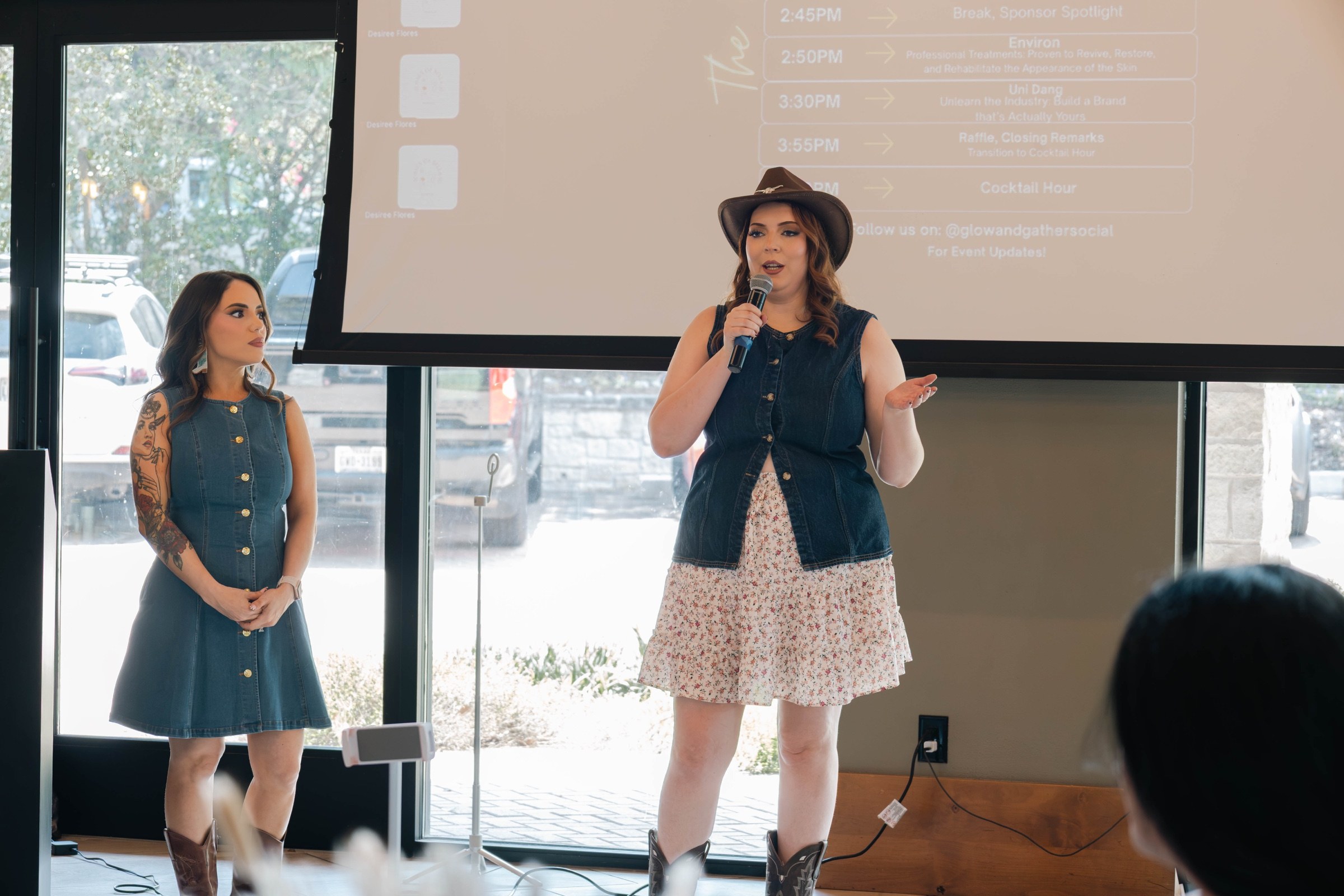 Two Glow & Gather presenters on stage as one speaks into a microphone